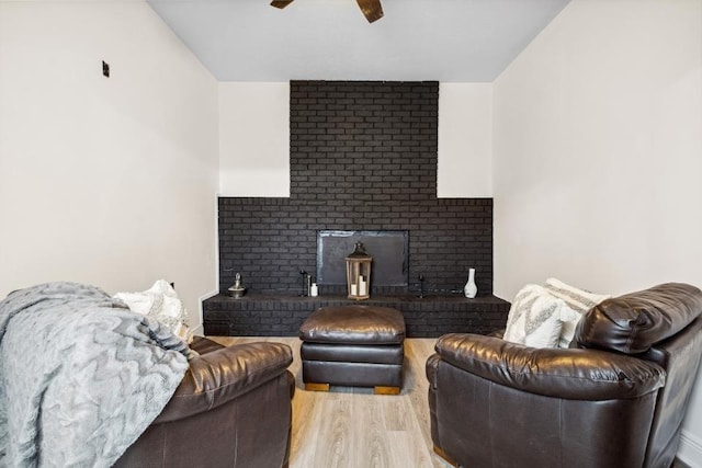 living room featuring a fireplace, ceiling fan, and light hardwood / wood-style floors