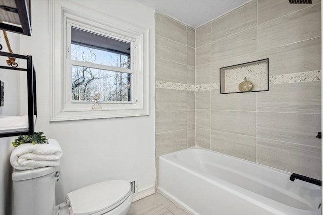 bathroom featuring toilet, tiled shower / bath combo, and tile patterned floors