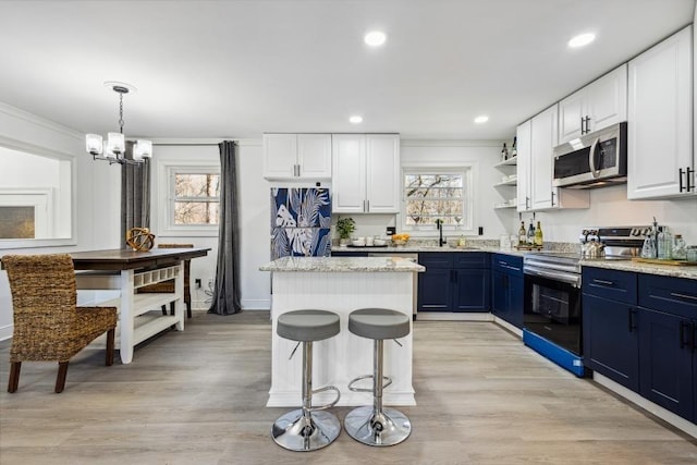 kitchen with white cabinetry, appliances with stainless steel finishes, blue cabinets, a kitchen island, and pendant lighting