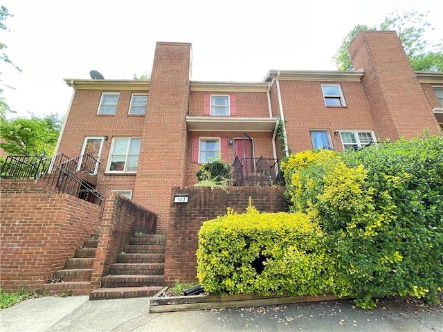 view of front facade with a chimney, stairway, and brick siding