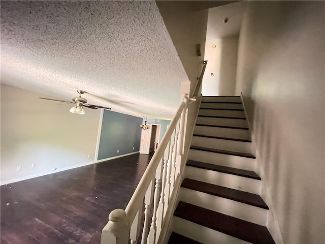 staircase featuring baseboards, a textured ceiling, ceiling fan, and wood finished floors