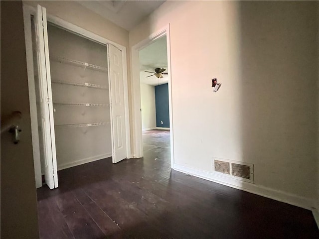 corridor featuring dark wood-style flooring, baseboards, and visible vents