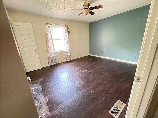 spare room with a ceiling fan, a textured ceiling, visible vents, wood finished floors, and baseboards