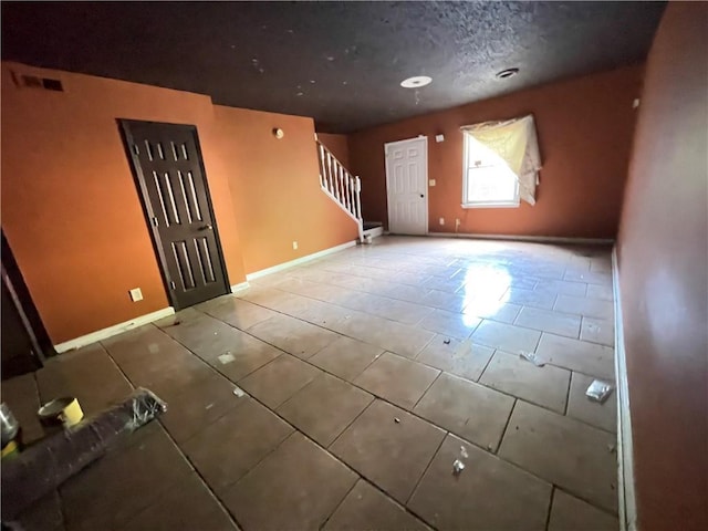 unfurnished living room featuring tile patterned flooring, stairs, baseboards, and visible vents
