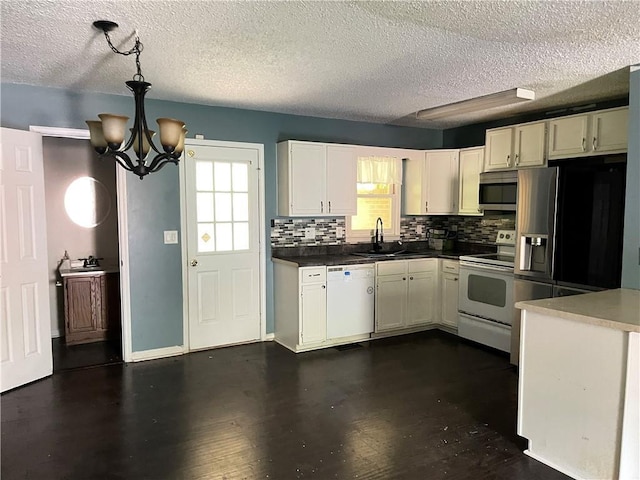 kitchen with an inviting chandelier, a sink, white appliances, white cabinetry, and tasteful backsplash