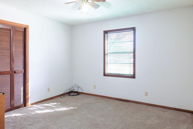 carpeted empty room featuring ceiling fan and a textured ceiling