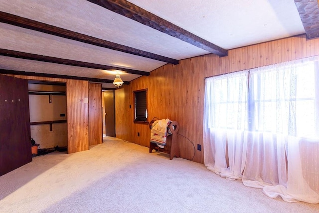 unfurnished room featuring beamed ceiling, carpet flooring, and wood walls