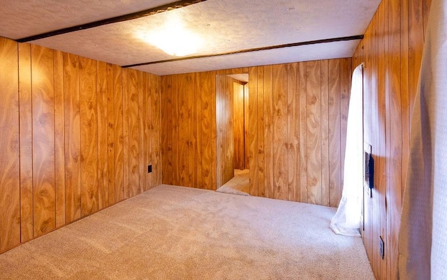 carpeted spare room featuring wood walls