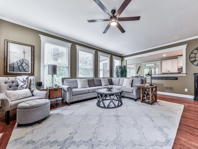 living area with crown molding, a ceiling fan, wood finished floors, and baseboards