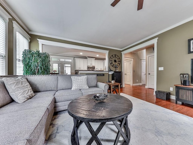 living room with crown molding, a ceiling fan, wood finished floors, baseboards, and recessed lighting
