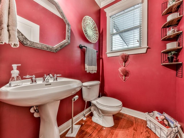 bathroom with baseboards, toilet, wood finished floors, and ornamental molding