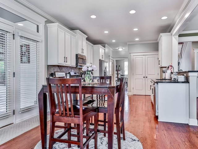 dining space with crown molding, recessed lighting, and wood finished floors