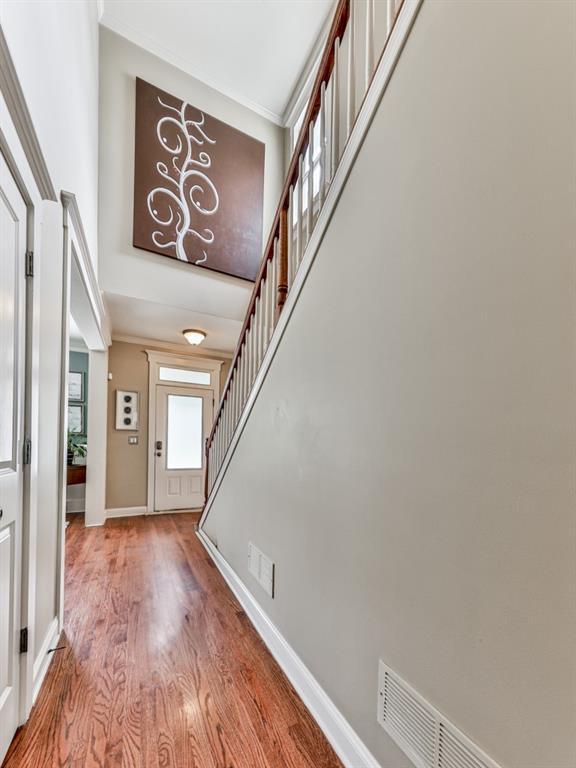 entryway featuring wood finished floors, stairs, a high ceiling, baseboards, and ornamental molding
