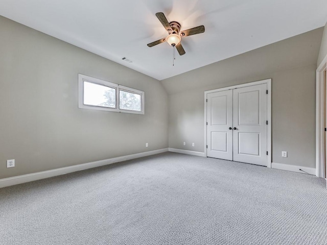 unfurnished bedroom with carpet floors, baseboards, a closet, lofted ceiling, and ceiling fan