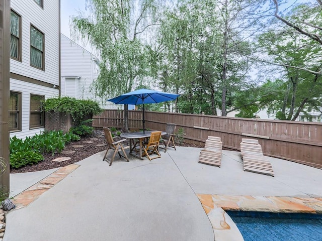 view of patio featuring fence, outdoor dining space, and a pool