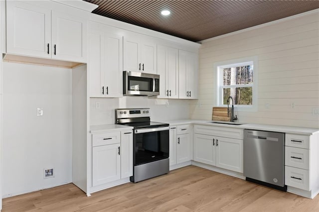 1337 Fairfield Dr, Lilburn, GA 30047 - kitchen with stainless steel appliances, light countertops, white cabinets, light wood-type flooring, and recessed lighting