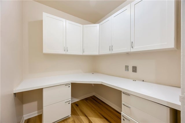 unfurnished office with baseboards, light wood finished floors, and built in study area
