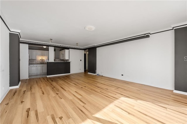unfurnished living room with baseboards, ornamental molding, and light wood-style floors