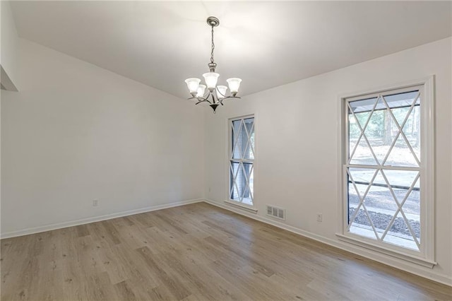 spare room featuring light hardwood / wood-style flooring and a chandelier