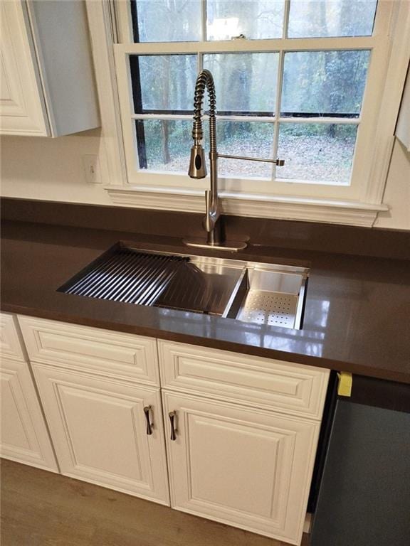 details with dishwasher, white cabinetry, and sink