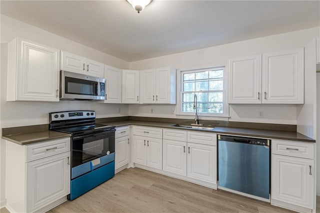 kitchen with white cabinets, light wood-type flooring, stainless steel appliances, and sink