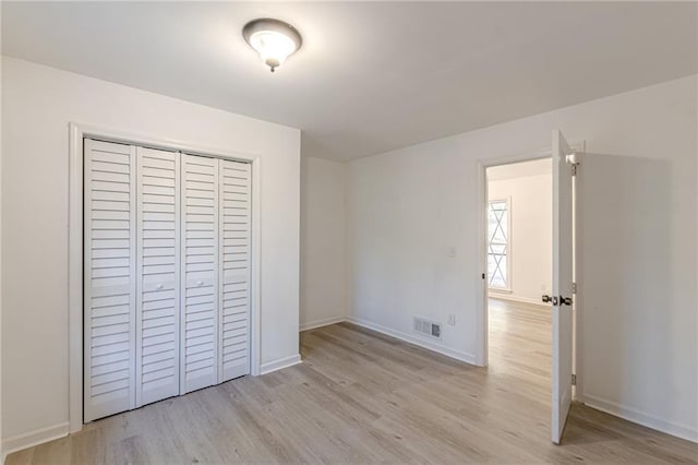 unfurnished bedroom with light wood-type flooring and a closet