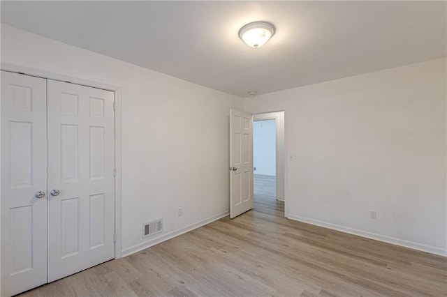 unfurnished bedroom featuring a closet and light wood-type flooring