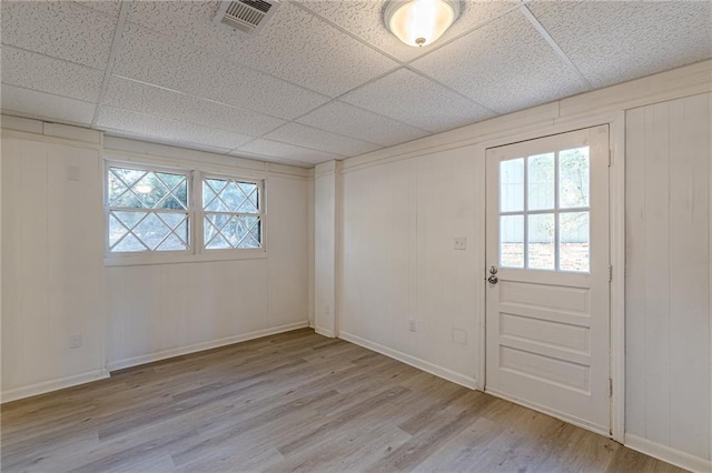 spare room featuring a drop ceiling and light hardwood / wood-style floors