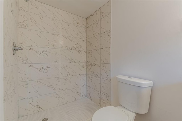 bathroom featuring tiled shower and toilet