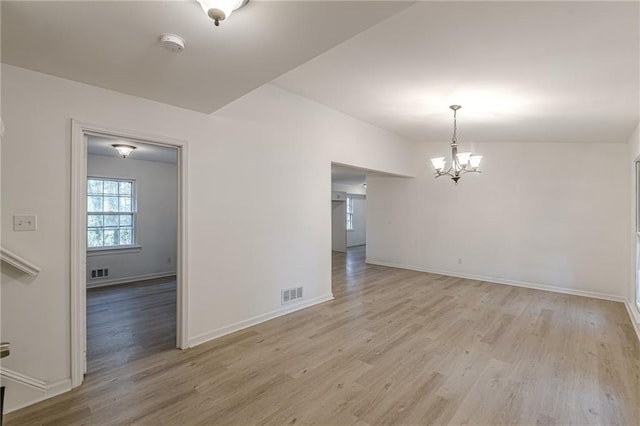 unfurnished room with a notable chandelier, light hardwood / wood-style floors, and lofted ceiling