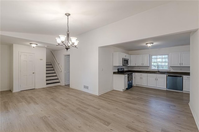 kitchen with pendant lighting, lofted ceiling, white cabinets, light hardwood / wood-style flooring, and stainless steel appliances