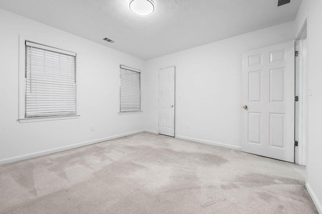 carpeted empty room featuring a textured ceiling