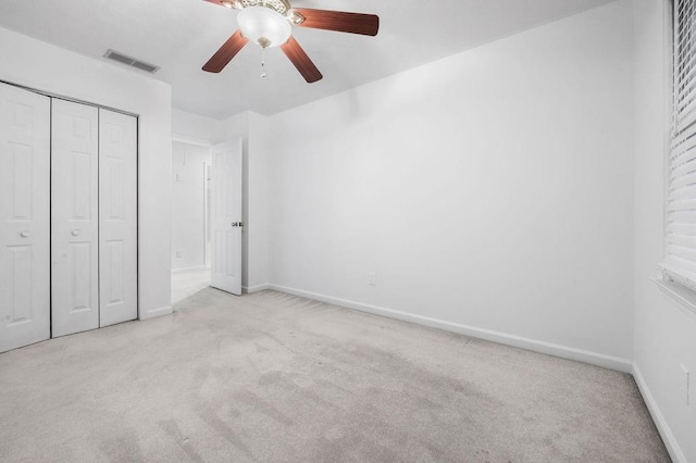 unfurnished bedroom featuring ceiling fan, light colored carpet, and a closet