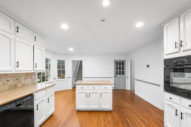 kitchen featuring light hardwood / wood-style flooring, white cabinetry, backsplash, black appliances, and ornamental molding