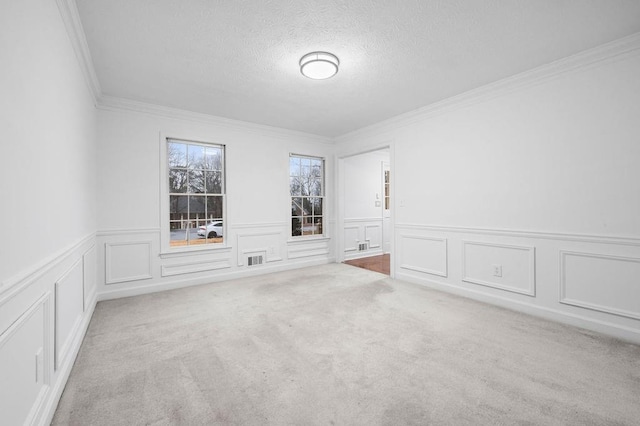 spare room featuring ornamental molding, light carpet, and a textured ceiling