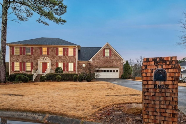 colonial-style house featuring a garage and a lawn