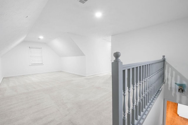 bonus room with lofted ceiling and light carpet