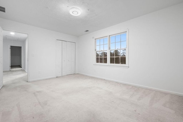 unfurnished bedroom featuring light colored carpet, a closet, and a textured ceiling