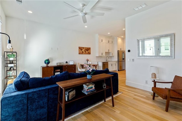 living room featuring ceiling fan, sink, and light hardwood / wood-style floors