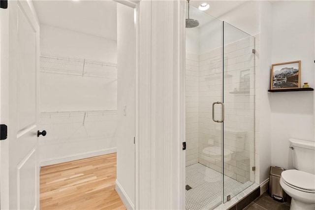 bathroom featuring an enclosed shower, wood-type flooring, and toilet