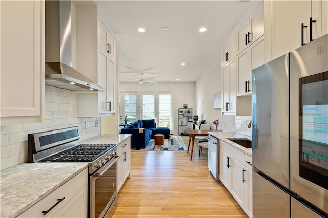 kitchen with wall chimney exhaust hood, stainless steel appliances, and white cabinetry