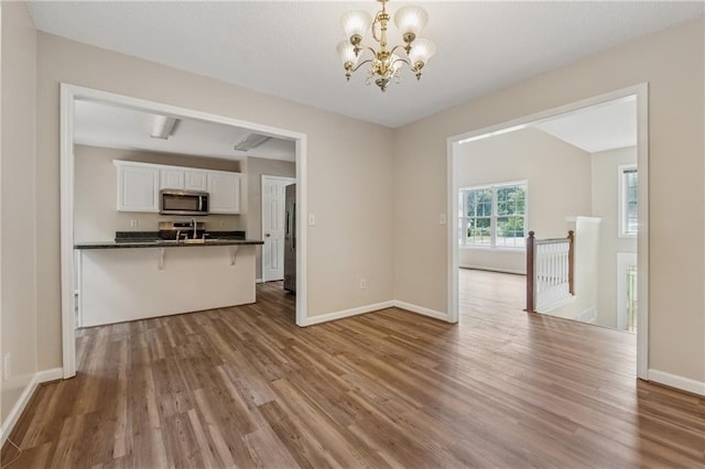 4958 Alpine Ct, Winston, GA 30187 - unfurnished living room featuring wood finished floors, a chandelier, and baseboards