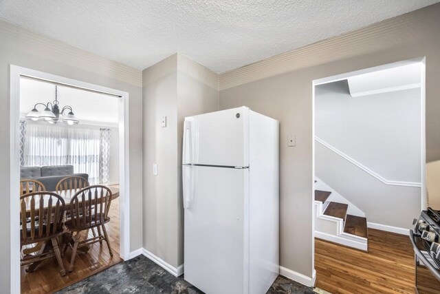 kitchen with a notable chandelier, freestanding refrigerator, gas stove, a textured ceiling, and wood finished floors