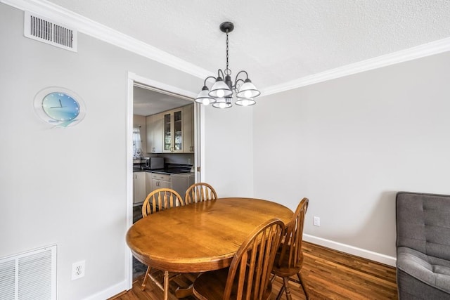 dining area featuring visible vents, crown molding, and wood finished floors