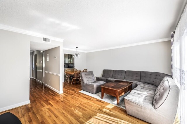 living area with ornamental molding, visible vents, baseboards, and wood finished floors