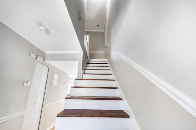 staircase with a textured ceiling and crown molding