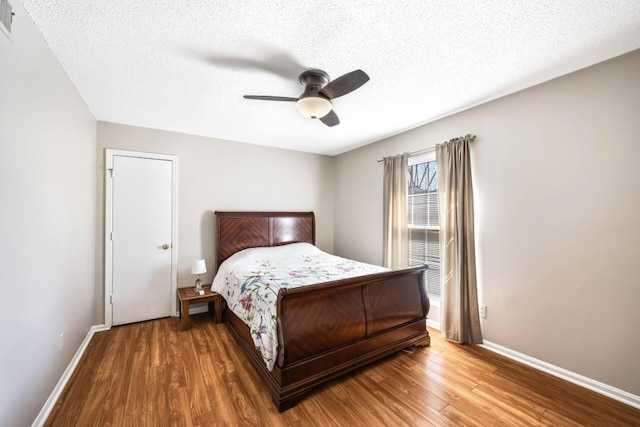 bedroom with a textured ceiling, baseboards, and wood finished floors