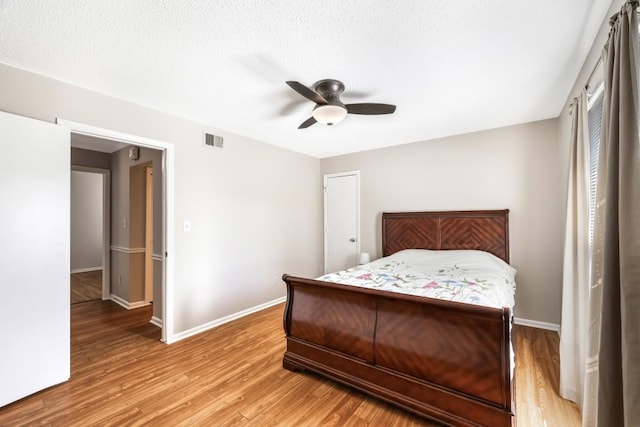 bedroom with baseboards, visible vents, ceiling fan, a textured ceiling, and light wood-type flooring