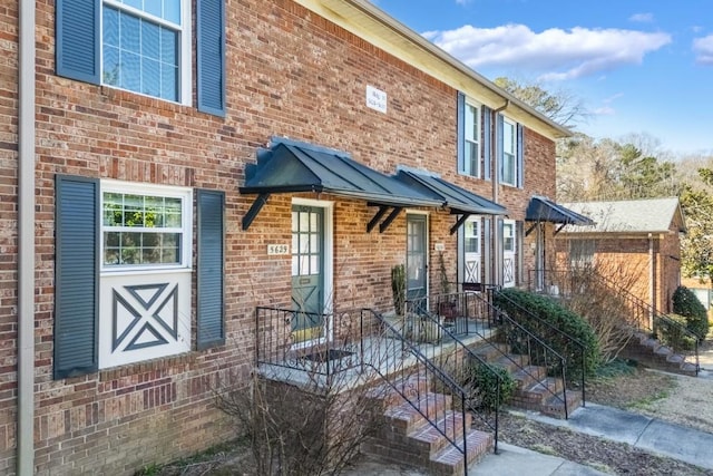 exterior space with a standing seam roof, brick siding, and metal roof