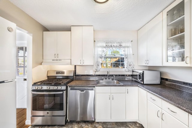 kitchen with stainless steel appliances, a textured ceiling, under cabinet range hood, white cabinetry, and a sink